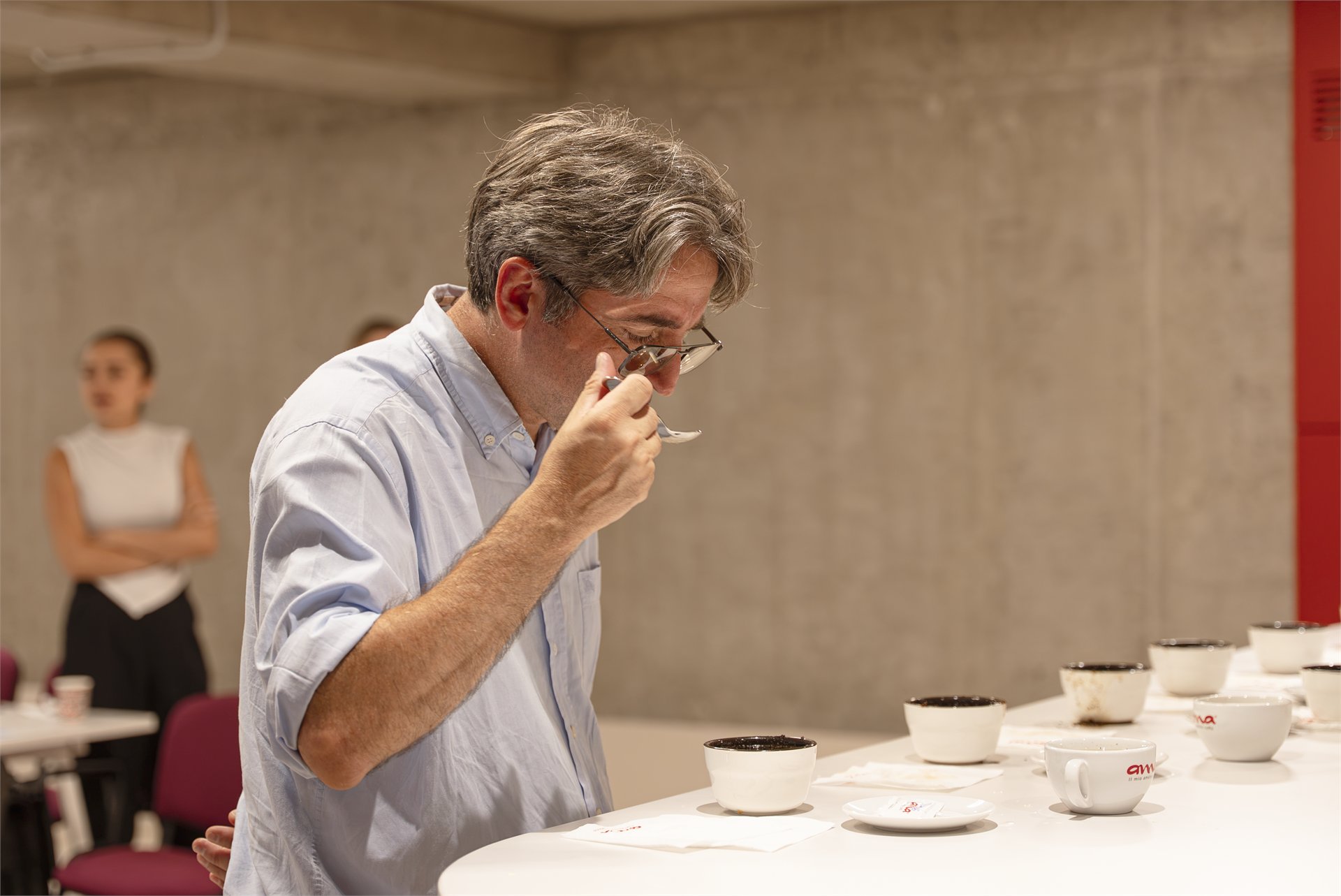 Trainer tasting coffee by spoon